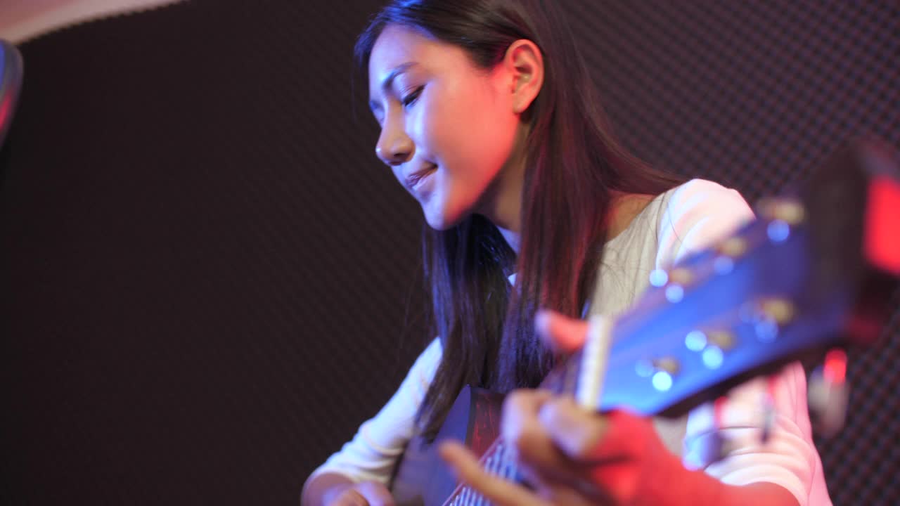 可爱的女人用吉他在录音棚录制原声歌曲视频素材