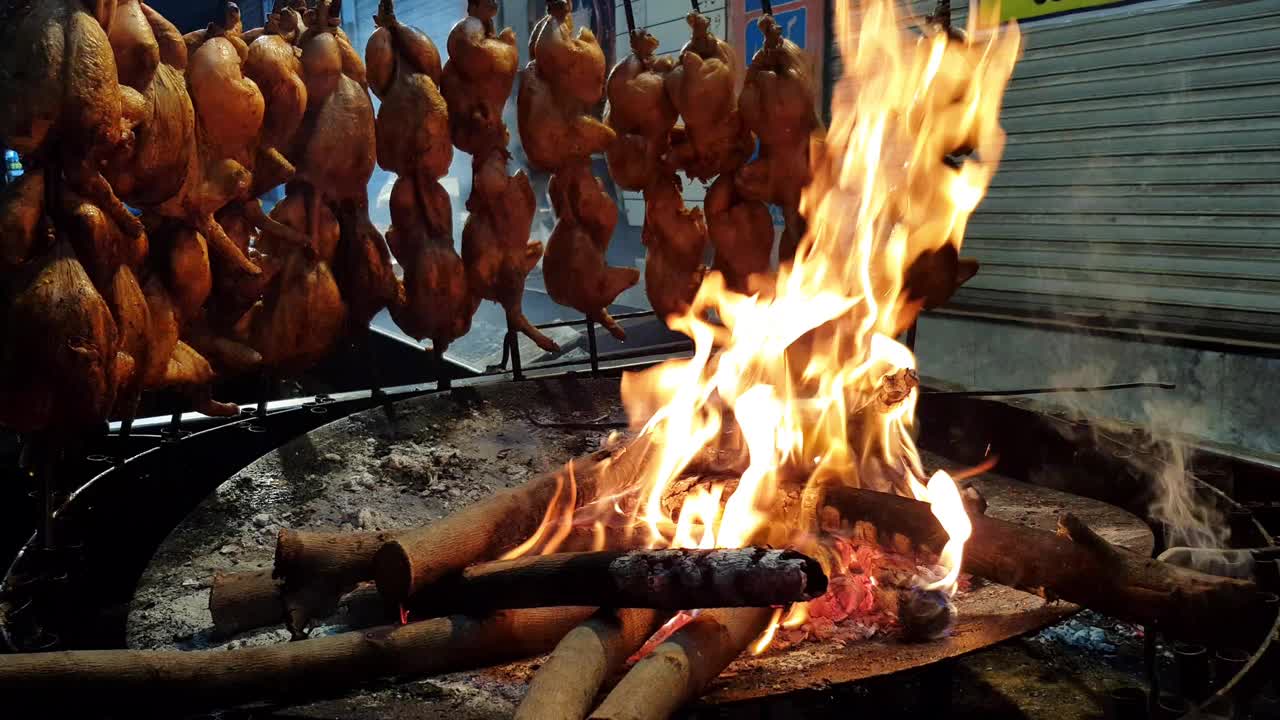 一种传统的鸡肉sajji(全鸡)，放在城市街道的火上烤。视频下载