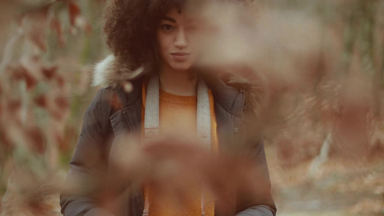 一个留着非洲式发型的年轻女子在树林里拍照视频下载