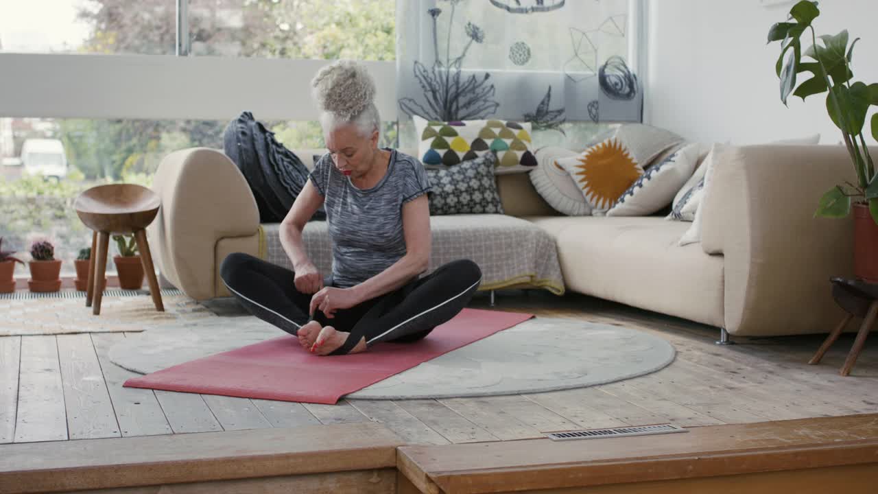 一位老妇人在客厅里准备练习瑜伽视频素材