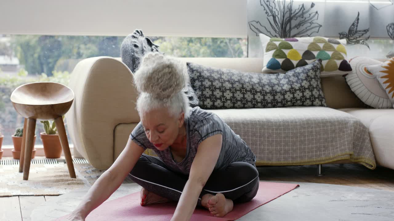 白发苍苍的老女人在客厅练习瑜伽视频素材