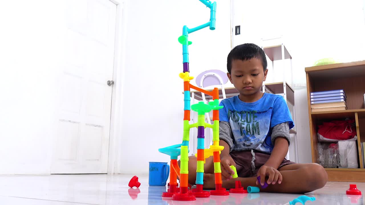 一个泰国男孩在客厅里玩玩具。视频下载