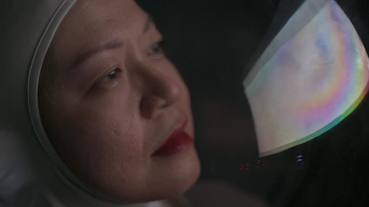亚洲华裔女宇航员从太空飞船上透过窗户看地球视频素材