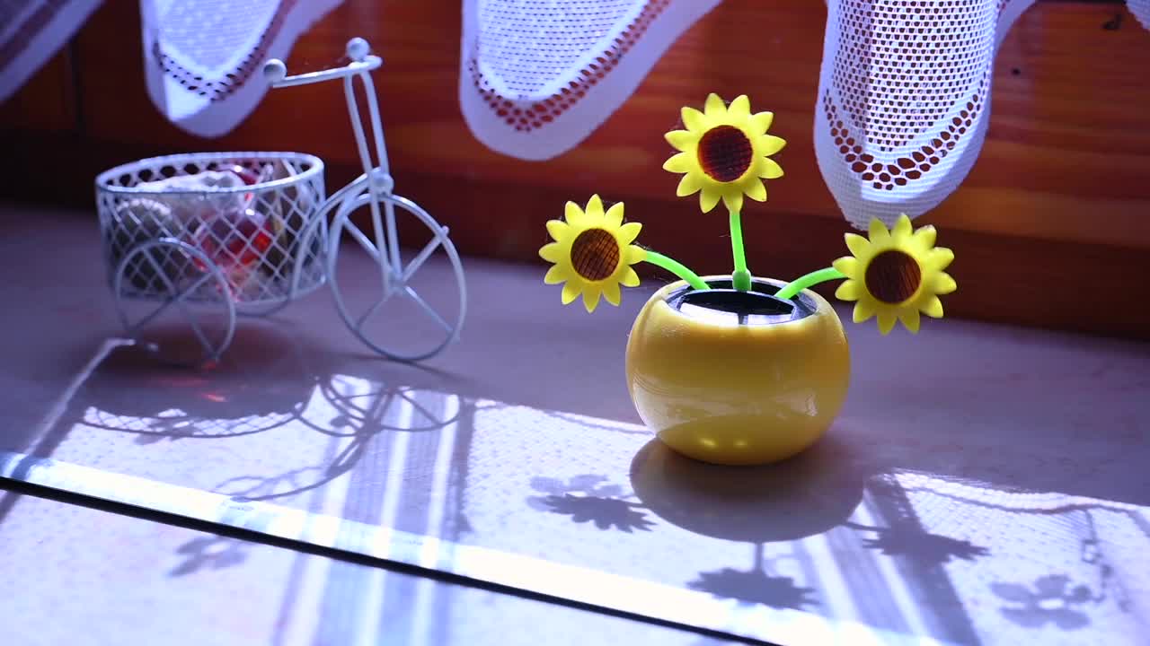 窗户上的太阳能塑料人工向日葵在代表可再生能源的阳光下移动。视频素材