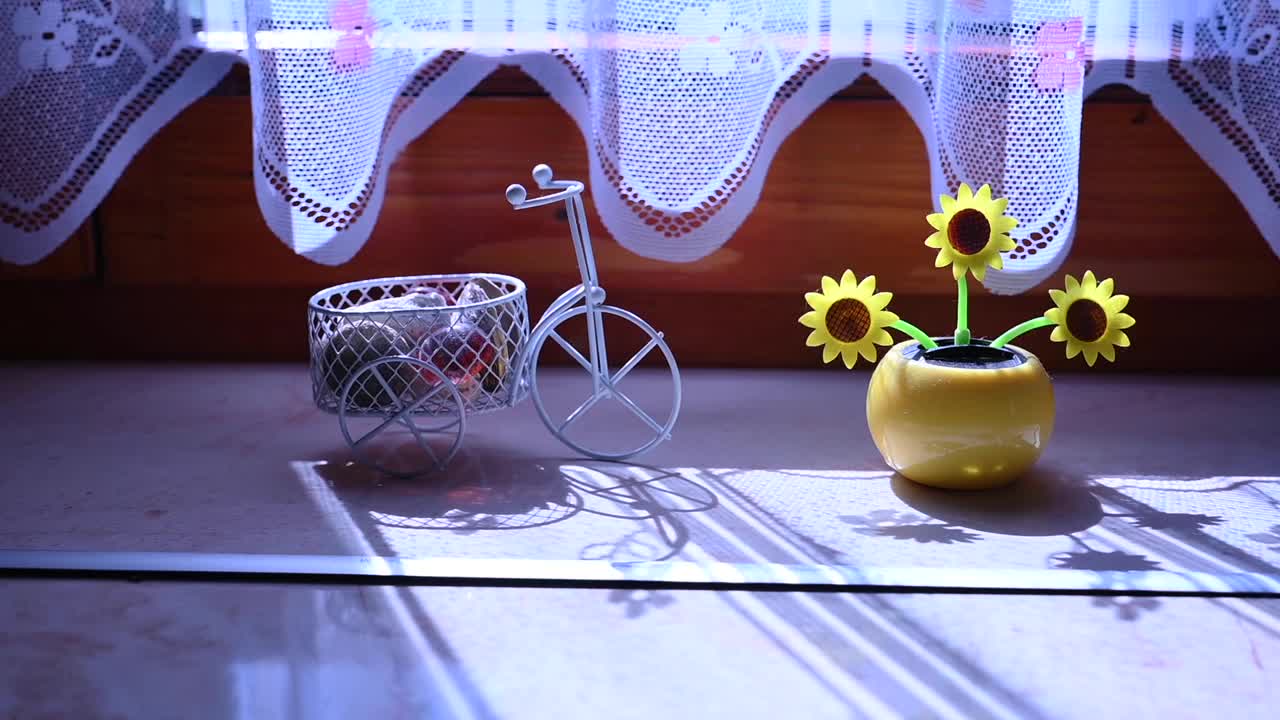 窗户上的太阳能塑料人工向日葵在代表可再生能源的阳光下移动。视频下载