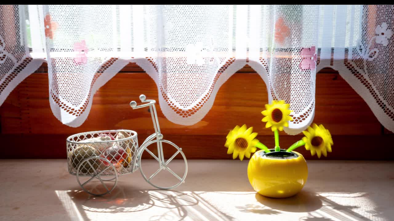 窗户上的太阳能塑料人工向日葵在阳光下移动，代表可再生能源。视频素材