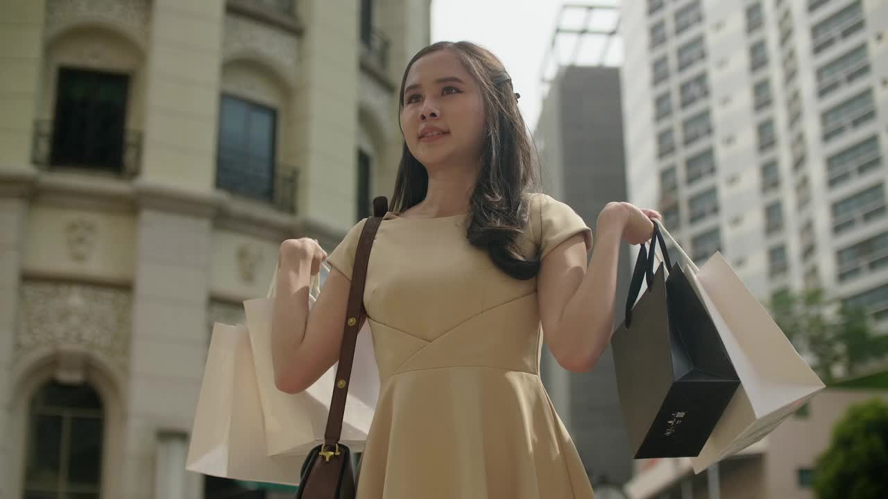 一个年轻的亚洲女人在商店里提着购物袋视频下载