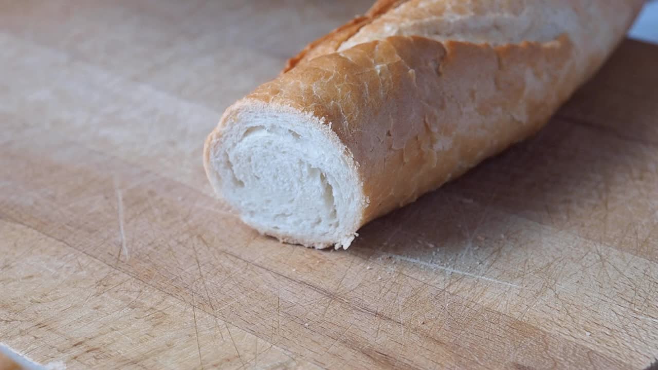 法式长棍面包是用刀在木制砧板上切成薄片的。视频素材