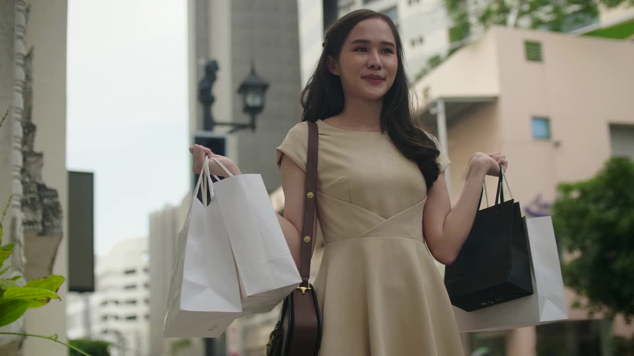 一个年轻的亚洲女人在商店里提着购物袋视频下载