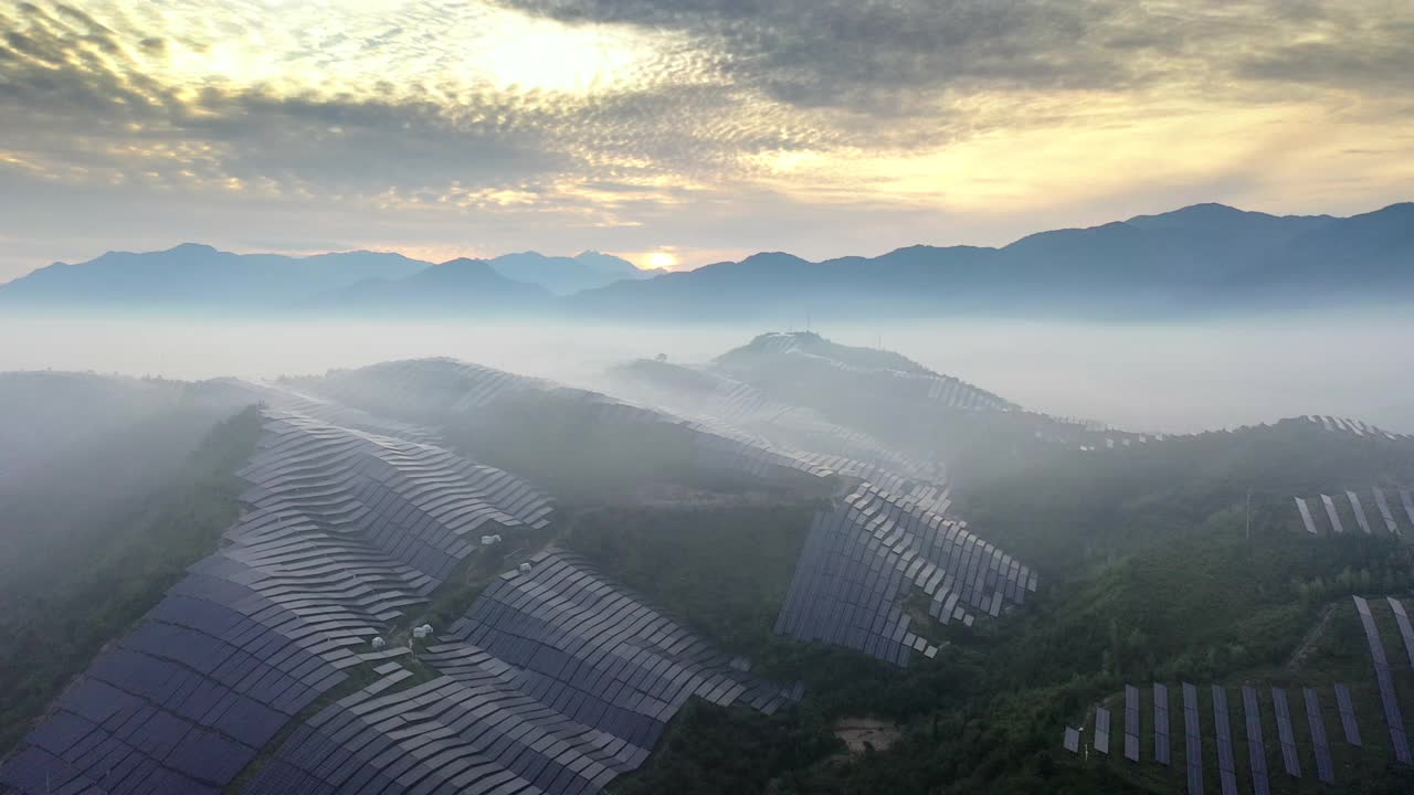 在日出的晨雾中，山顶太阳能发电厂的鸟瞰图视频下载