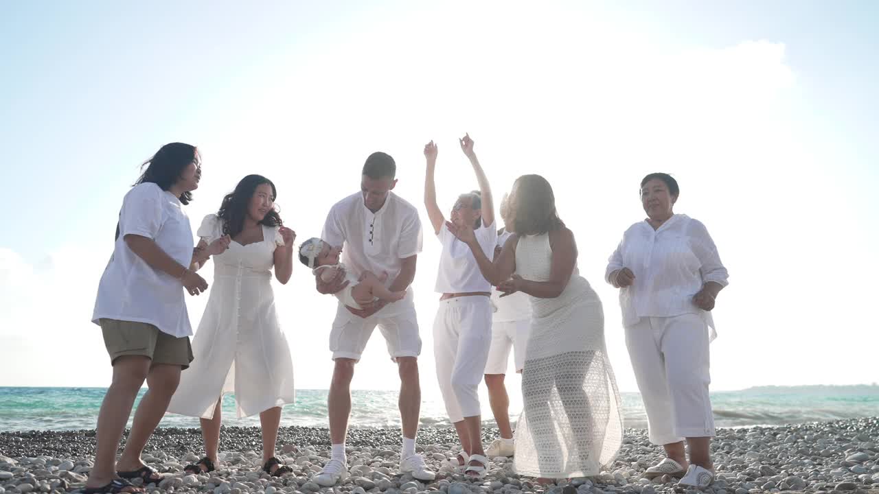 广角镜头兴奋的亚洲家庭在阳光下风景如画的地中海海滩上跳舞。快乐的男男女女在风景如画的亚热带旅游胜地享受夏日假期。缓慢的运动。视频素材