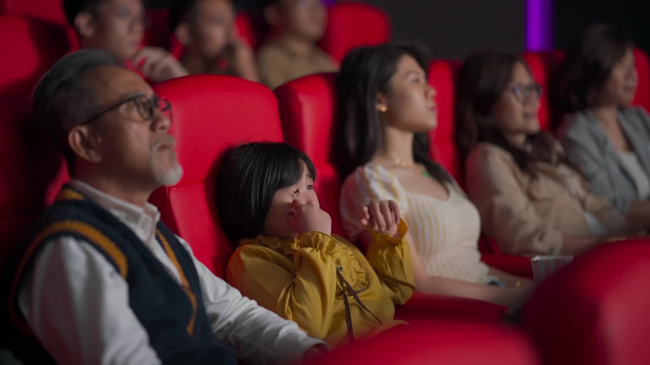亚洲华人活跃的老人和他的孙女在电影院看伤感感人的电影视频素材