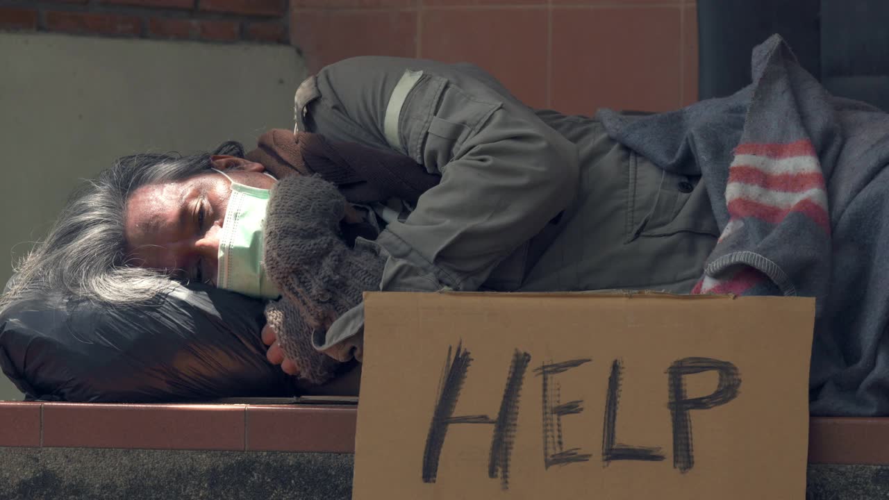 4K戴着医用口罩的无家可归老人睡在城市的人行道上。视频下载