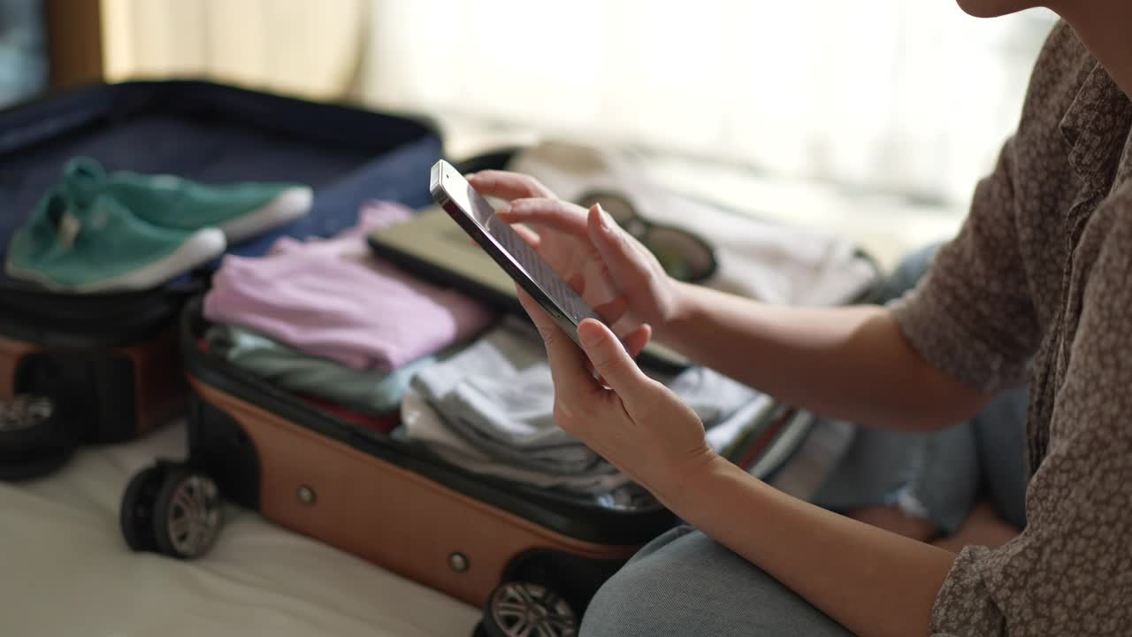 女人在度假打包行李时用电话核对清单视频下载