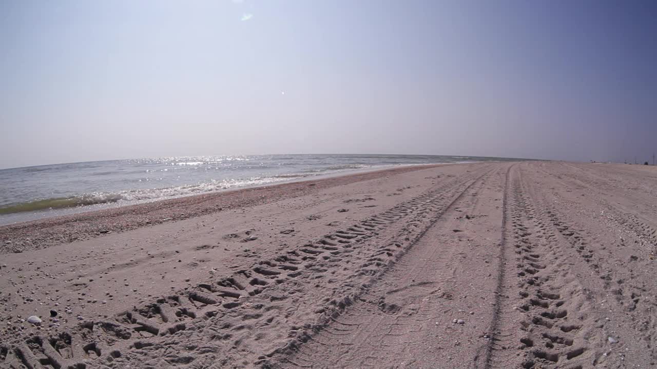 稳定的摄像机实时拍摄男子在海滩附近的沙滩上奔跑视频素材