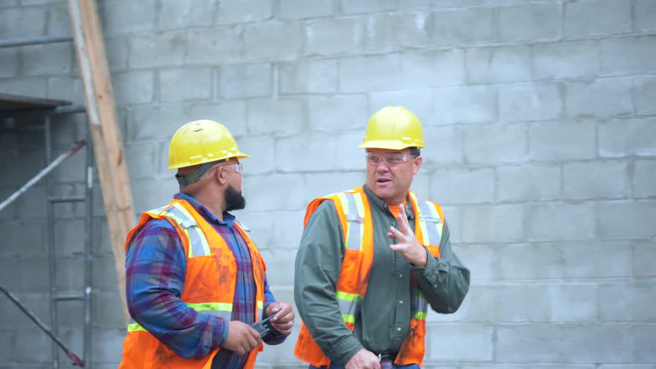 两名建筑工人在工地边走边聊视频素材