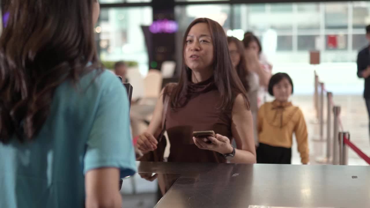 亚洲华人女性顾客在售票处使用非接触式支付移动应用程序购票。视频素材