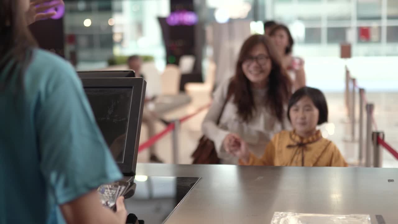 亚洲华裔单身母亲带着女儿在售票处用非接触式移动支付app买票。视频素材