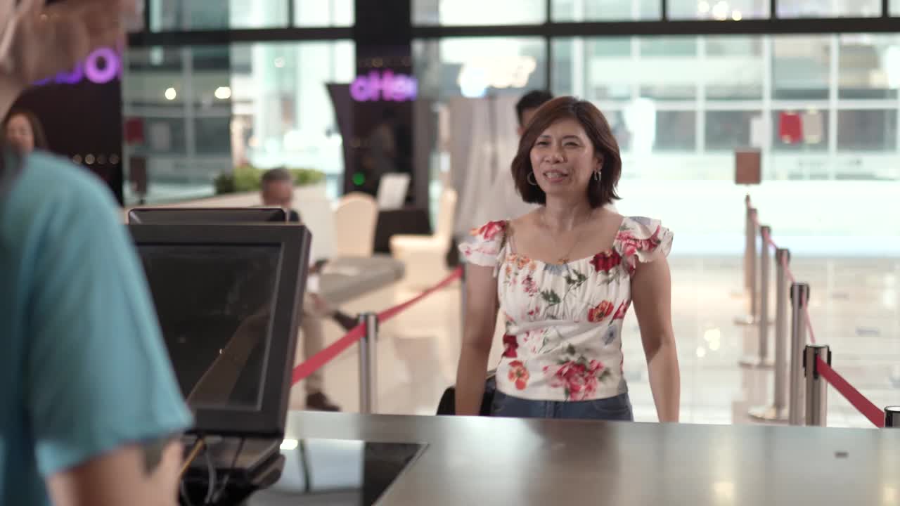 亚洲华人女性顾客在售票处使用非接触式支付移动应用程序购票。视频素材