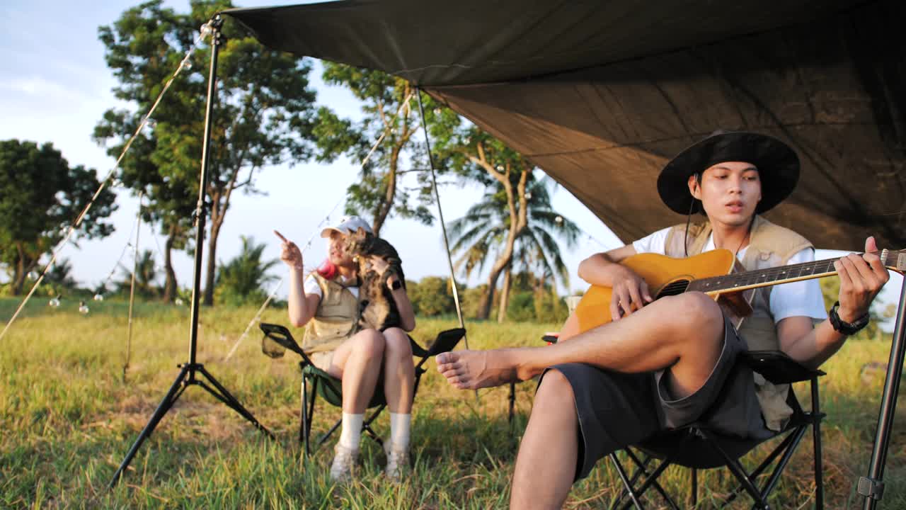 在帐篷前一起弹吉他、唱歌。野营视频素材