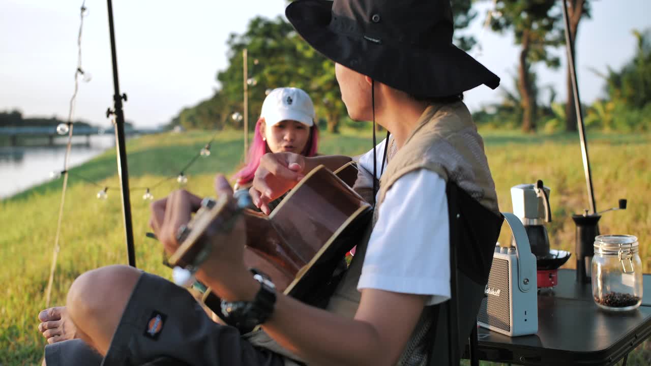 在帐篷前一起弹吉他、唱歌。野营视频素材