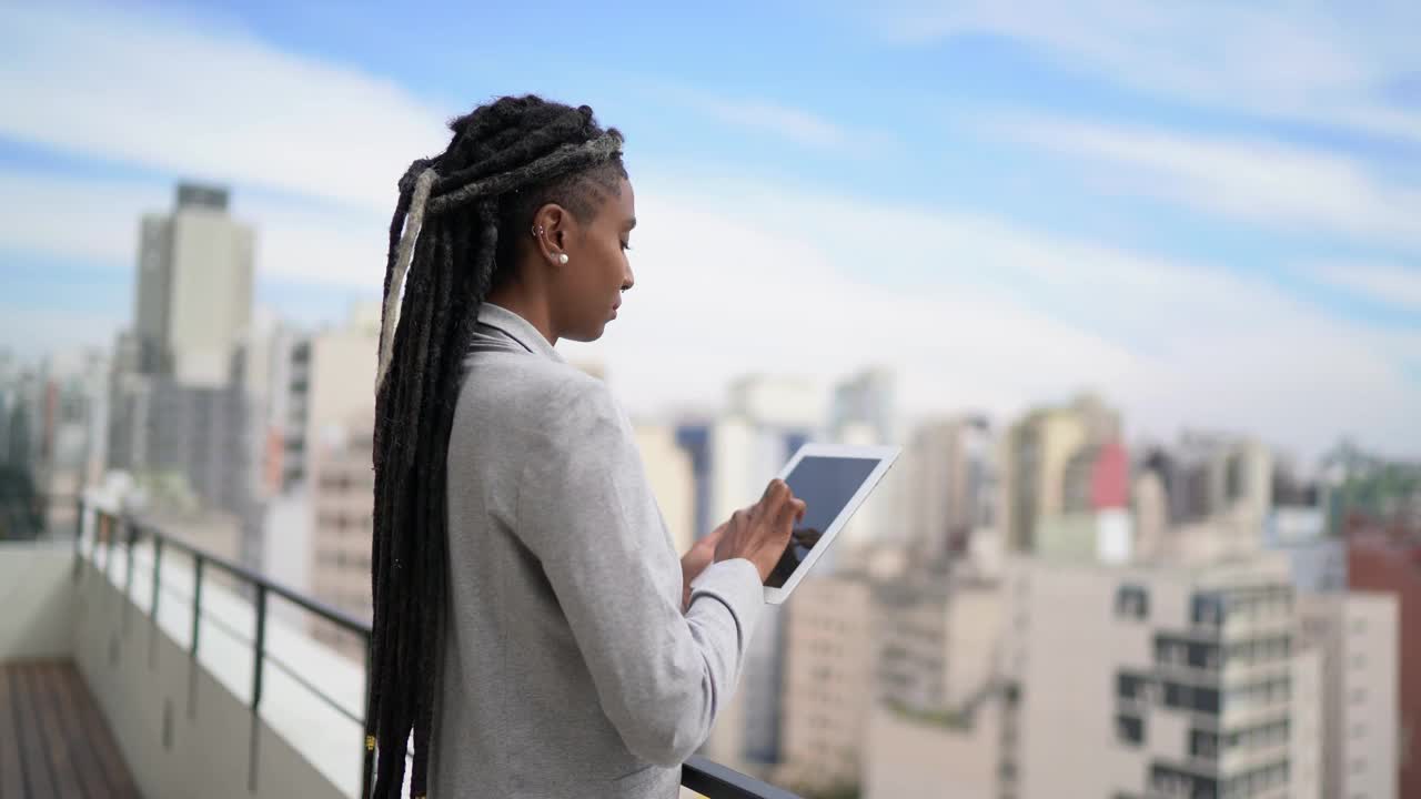 一位年轻的女商人在屋顶上思考和使用数字平板电脑视频下载
