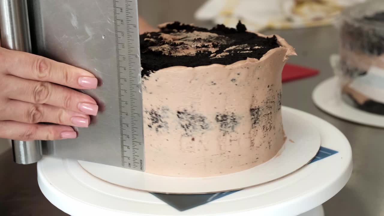 4K女糕点厨师在巧克力蛋糕上抹巧克力奶油，特写镜头。缓慢的运动。蛋糕制作过程。视频下载