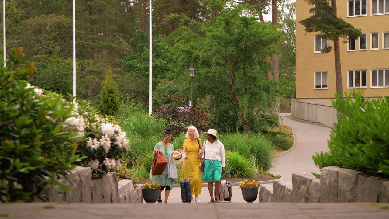 手持拍摄的老年女性朋友在度假期间带着行李走在人行道上视频素材