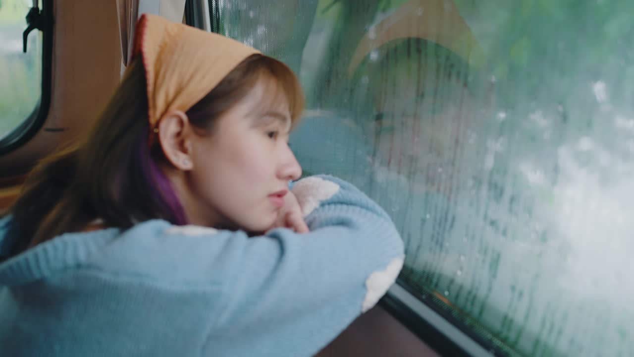 孤独的女人透过窗户看着雨。视频下载