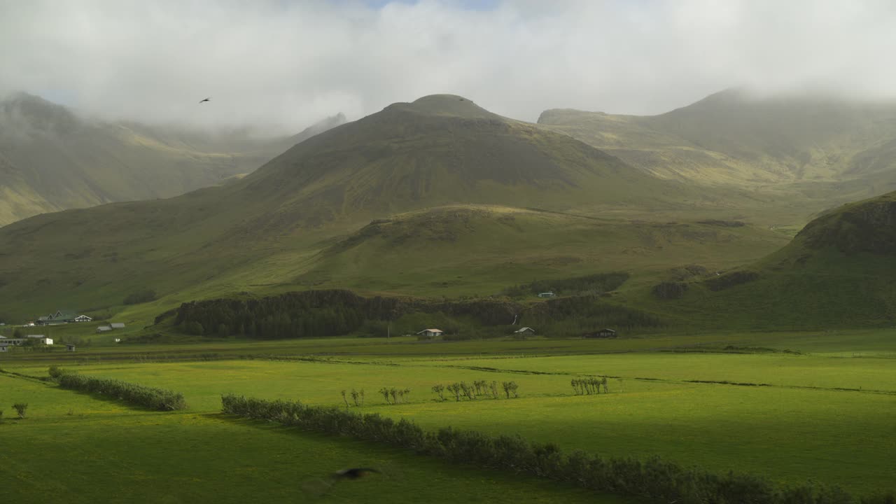 鸟瞰图的绿色田野附近的山脉/霍夫斯韦利，冰岛视频下载