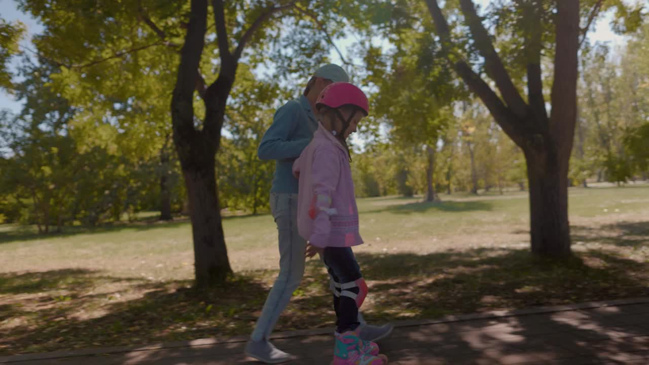 父母母亲教女孩戴着粉色头盔滑旱冰视频下载