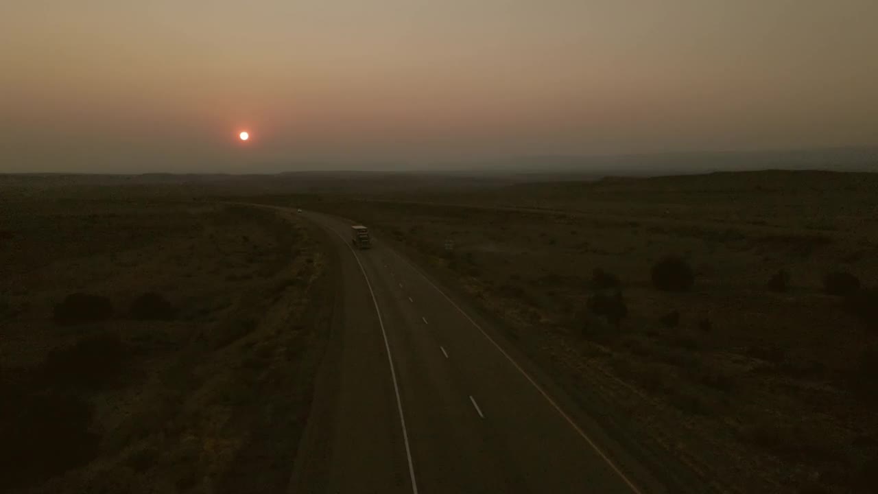 空中POV日落货物运输长途半挂车在美国西部州际公路上的乡村慢动作和实时视频视频素材
