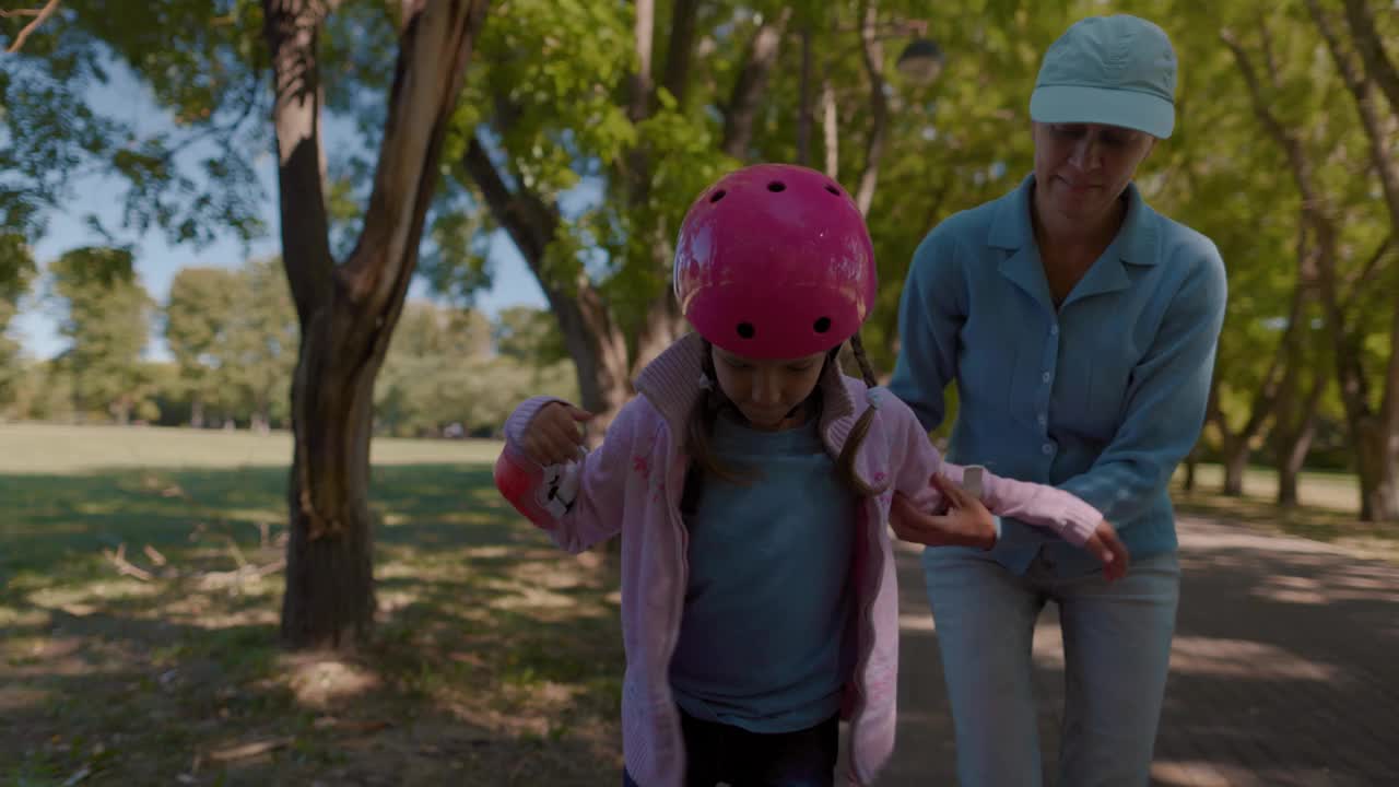父母母亲教女孩戴着粉色头盔滑旱冰视频下载