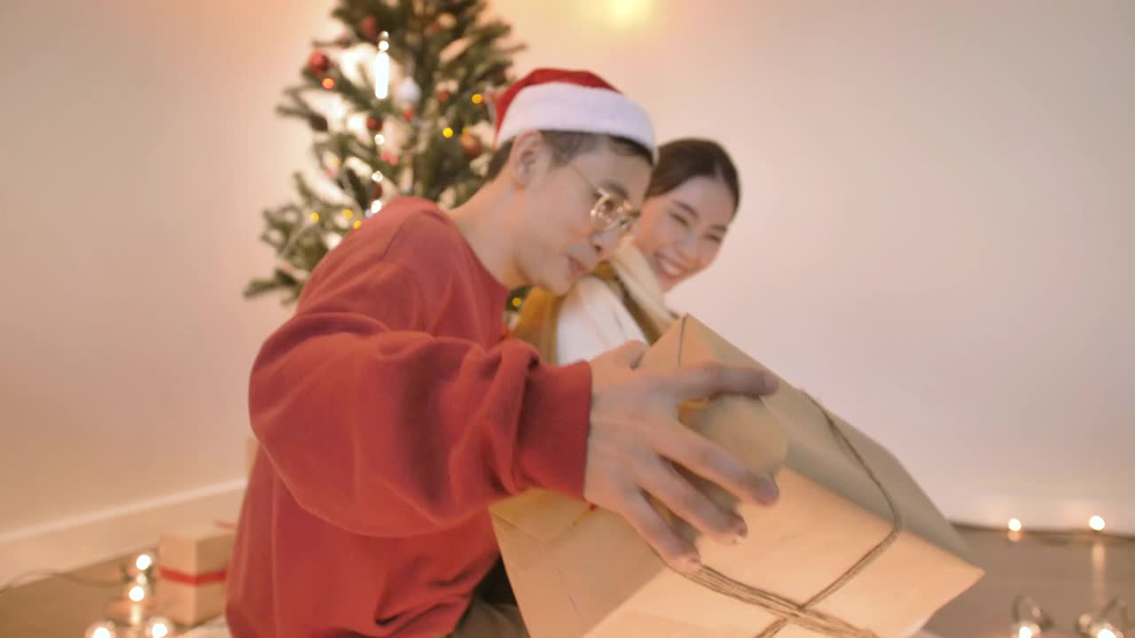 一个亚洲男人在圣诞节用礼物相机给他的女朋友一个惊喜。视频下载