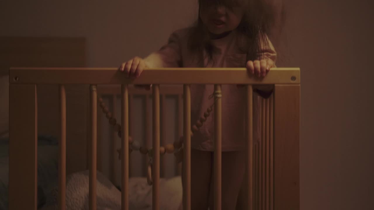 3岁的有趣的小女孩会在睡觉前跳到婴儿床上视频下载