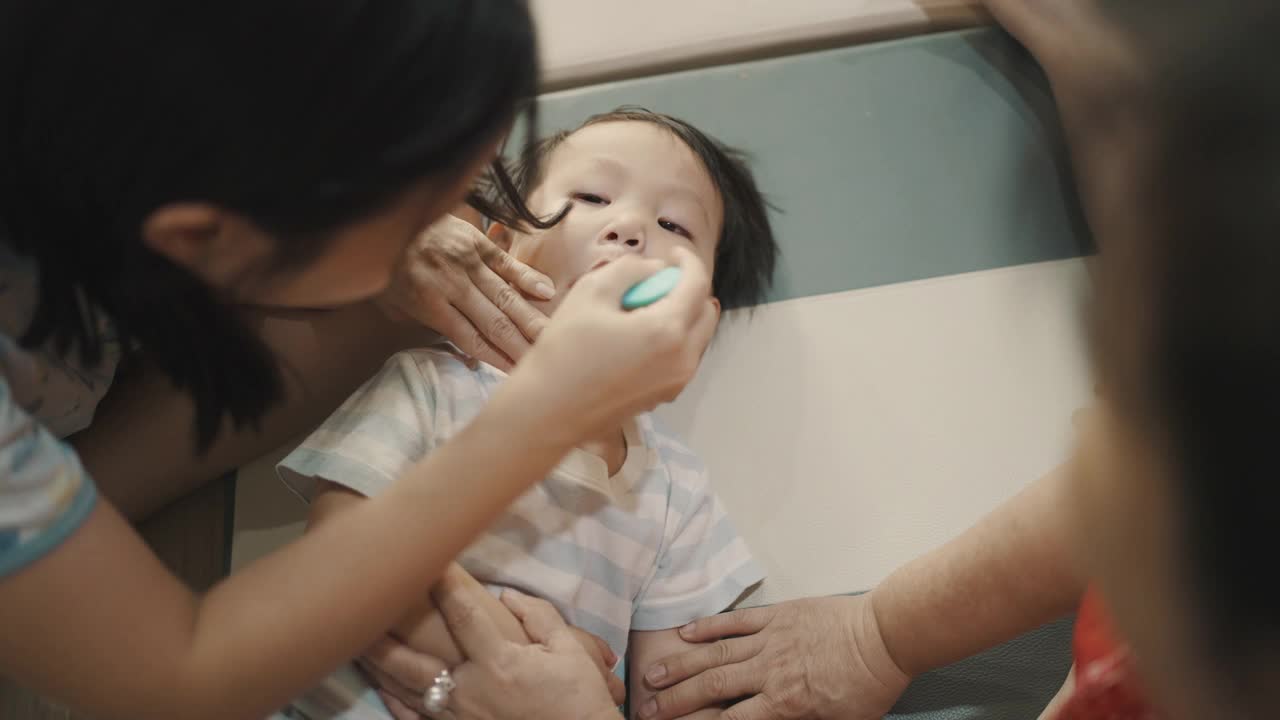 父母正在用牙刷帮儿子刷牙。视频下载