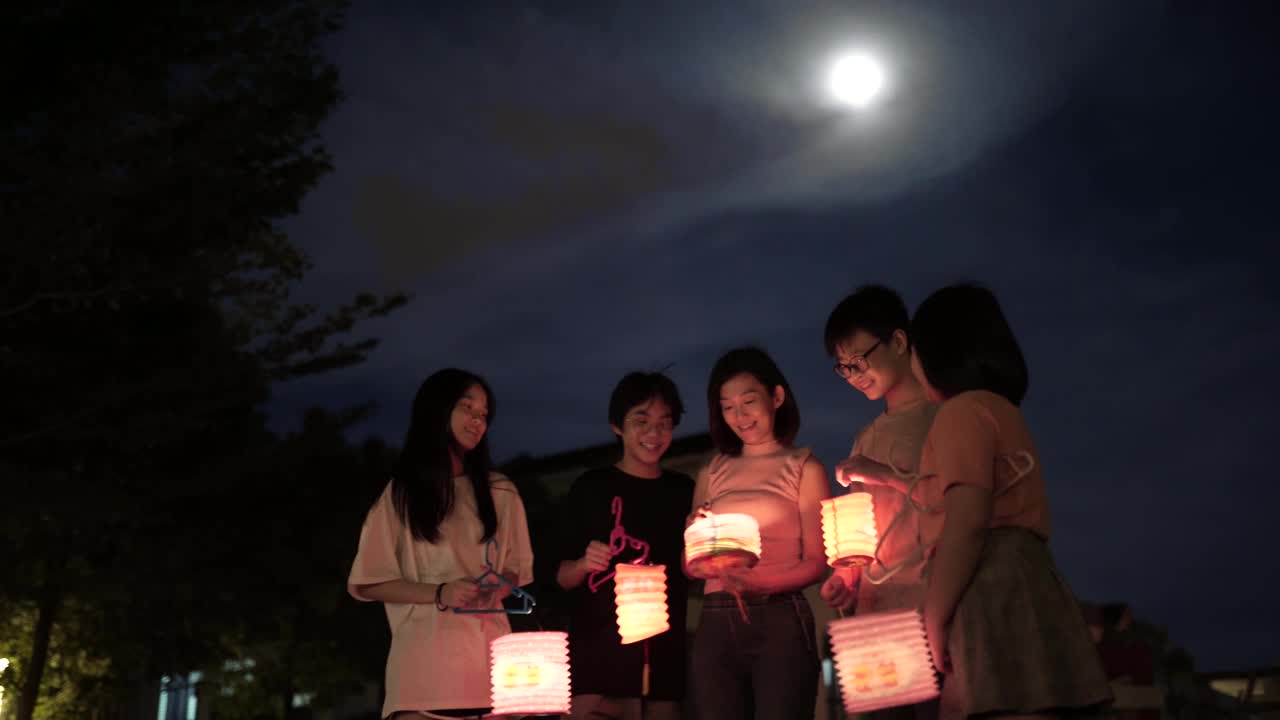 亞洲華人媽媽帶著孩子和侄子拿著紙燈籠，慶祝中秋節。視頻素材