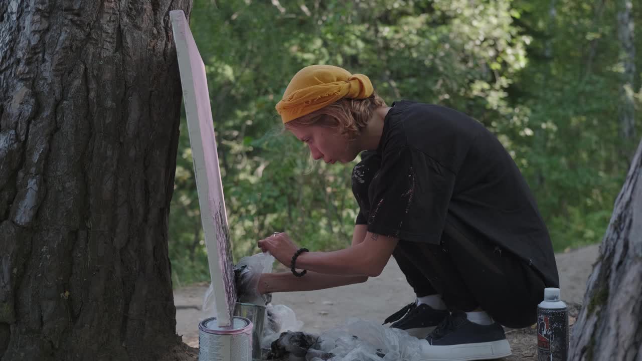 有创造力的女孩在森林里画画，蹲在画布前。视频下载