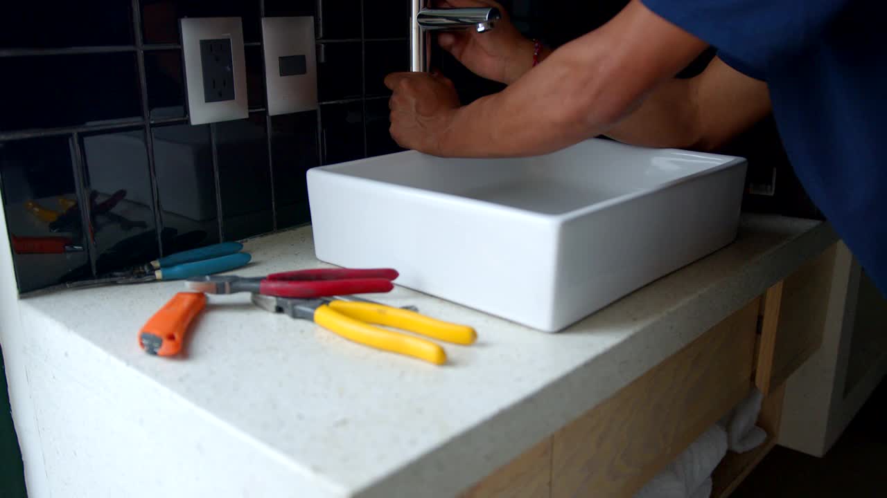 一位成年水管工正在客户家中调整浴室的水龙头视频下载