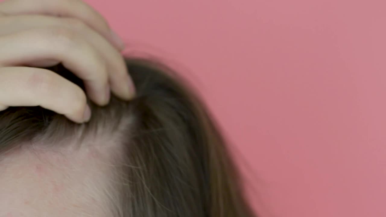 女孩触摸她的头发特写在粉红色的背景，脱发的概念。视频素材