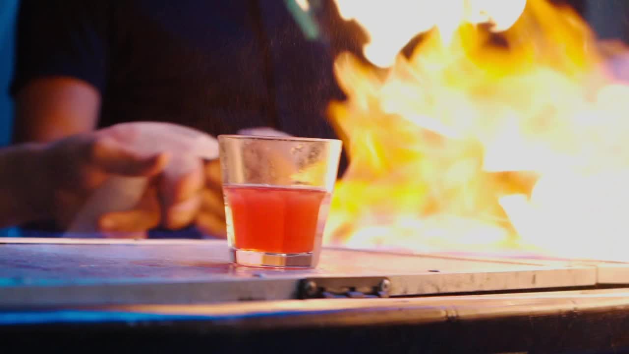 一个调酒师准备鸡尾酒并点燃酒精饮料的特写镜头视频素材