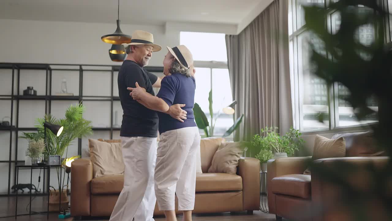 幸福退休亚洲人爱夫妇退休老夫妇在家，亚洲老夫妇一起跳舞笑笑喜气在客厅在家隔离呆在家封锁概念视频下载