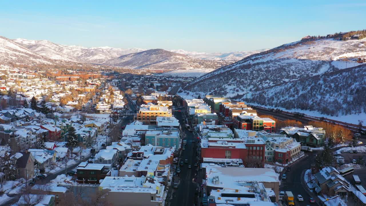空中向后移动在一个被雪覆盖的滑雪镇与安静的街道和明亮的早晨阳光-帕克城，犹他州视频下载