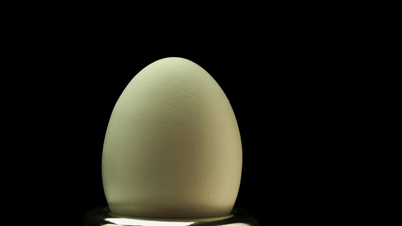 黑色背景下的鸡蛋在旋转。把太空蛋收集到蛋壳里视频素材