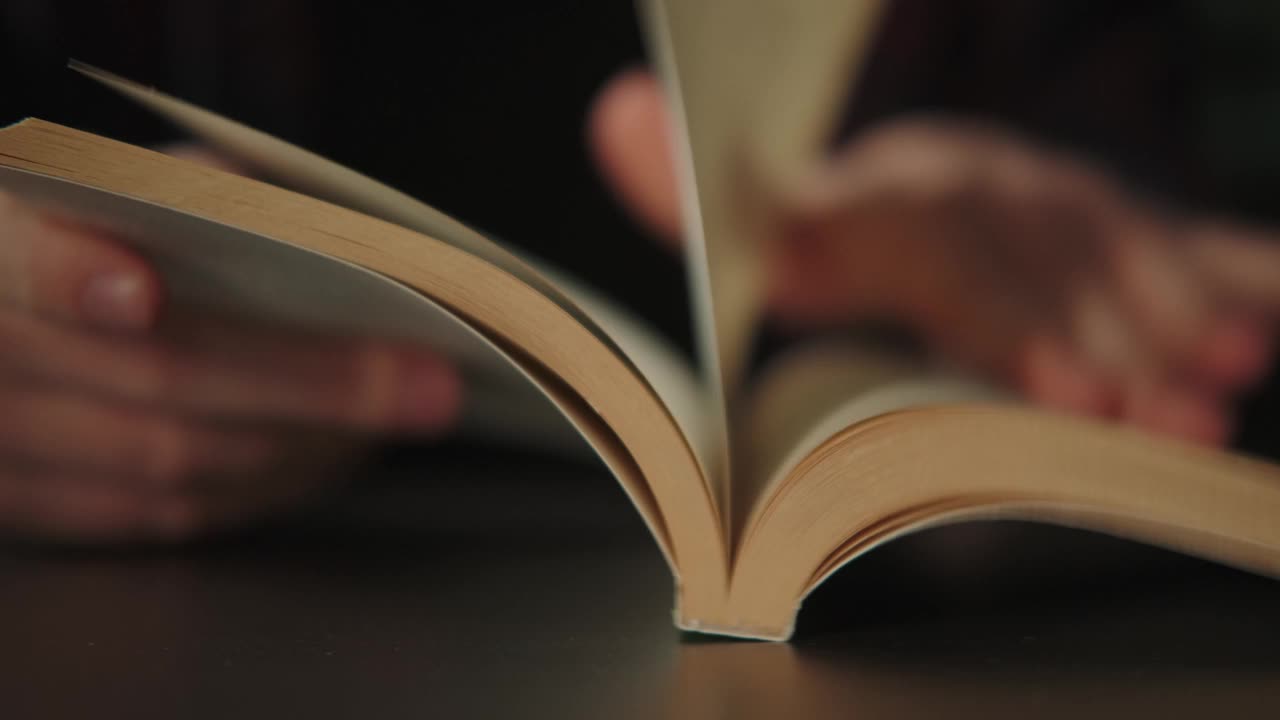 纸书放在桌上，一个人读文学，翻一页。视频下载