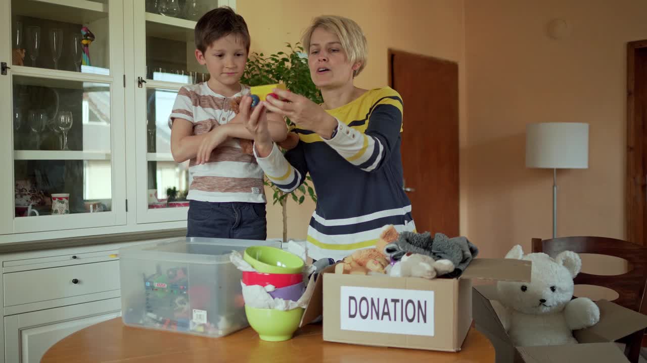 一个小男孩正在整理他的玩具盒，准备捐出不想要的玩具视频素材