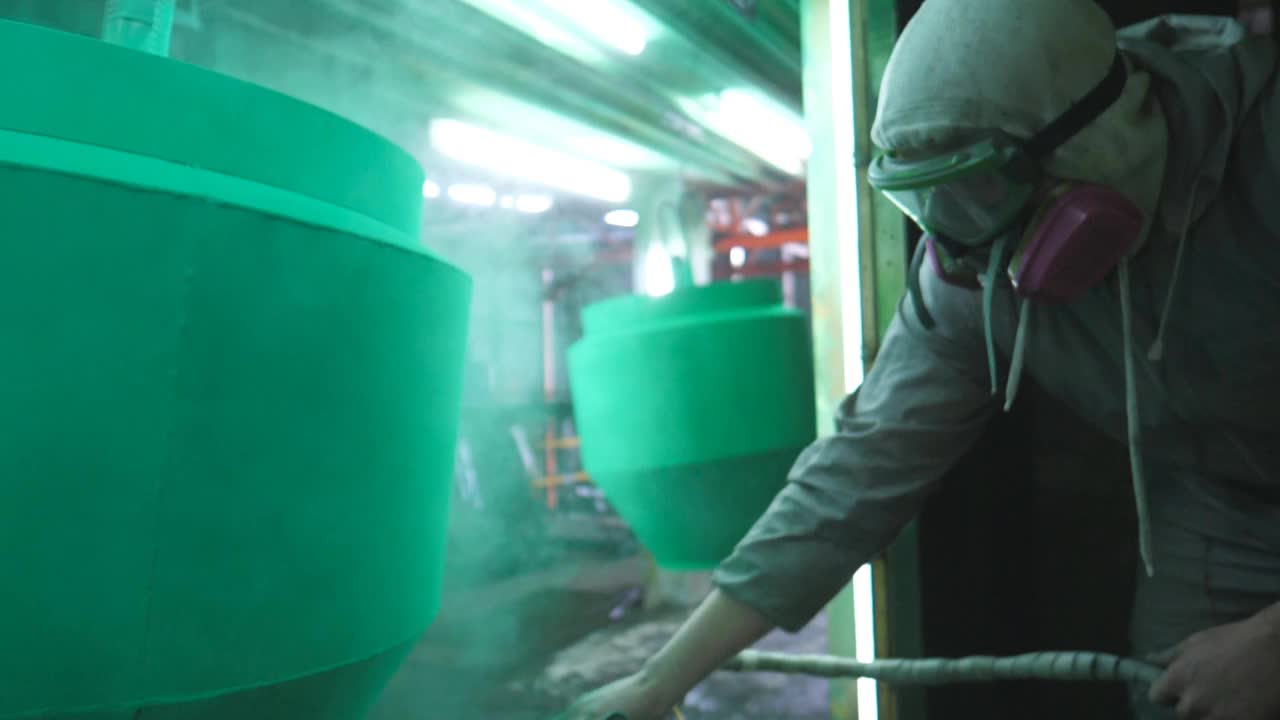 工人在油漆室的细节处喷涂绿色油漆。在工业工厂工作的油漆工。大师油漆细节在专门的车间。男人在生产中油漆零件。慢动作特写视频素材