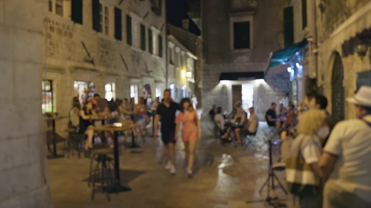散焦拍摄的人们在夏夜漫步在欧洲小镇的老中心。街头咖啡馆与游人交流、休憩。温馨浪漫的气氛视频素材