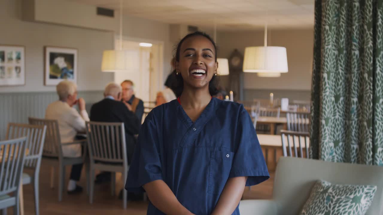 在养老院，微笑的女性护理人员站在老人的身后视频素材