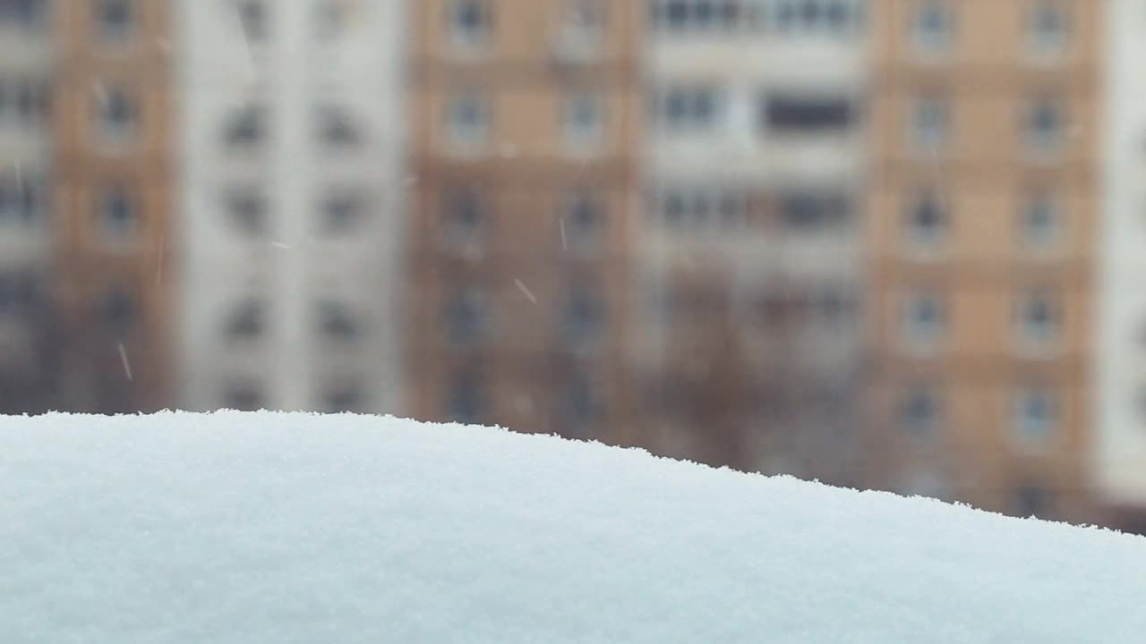 现代住宅窗口，雪景城市。窗台上的雪堆。冬天模糊背景。窗外又冷又下雪。视频素材